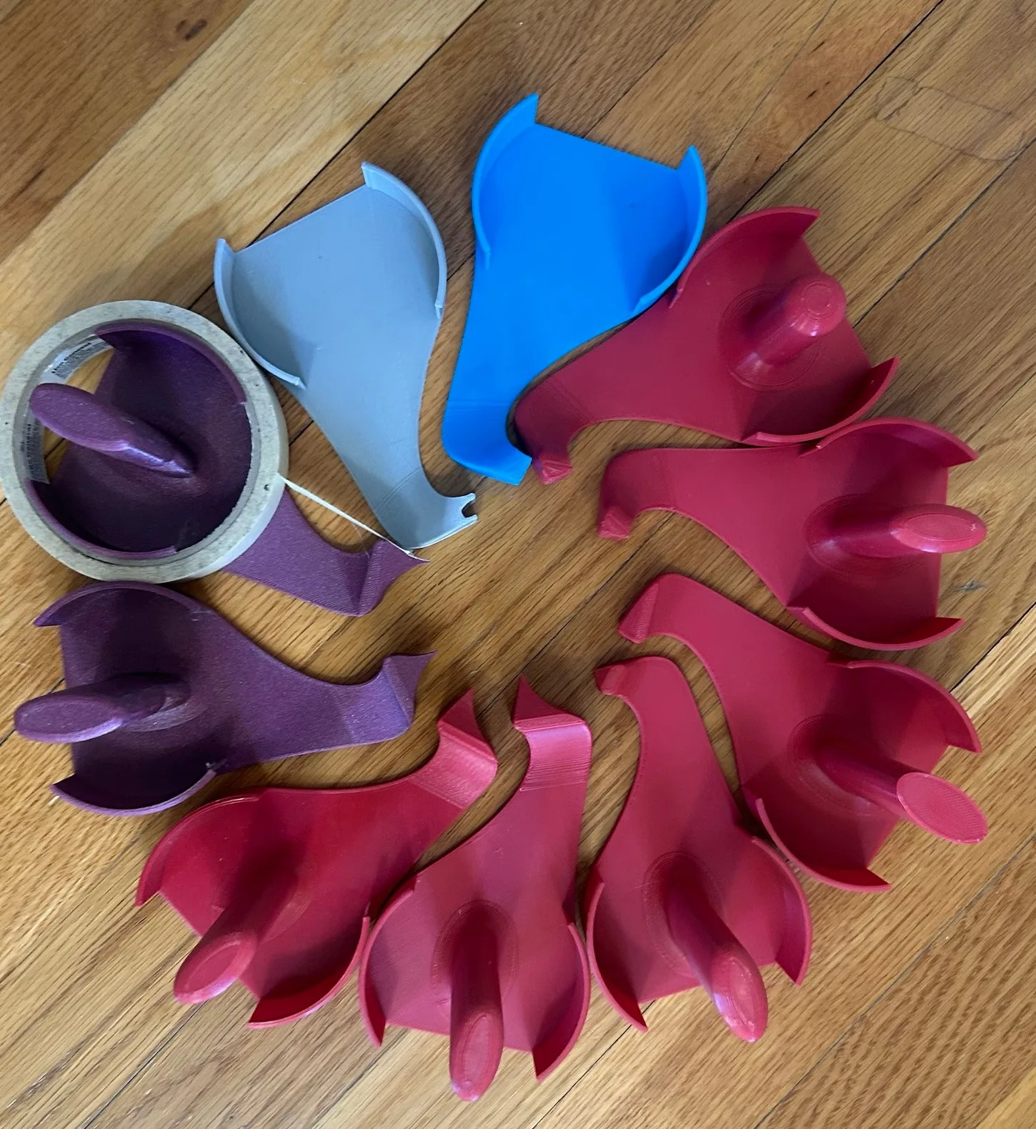 Printed prototypes side by side; one purple version holds a roll of tape