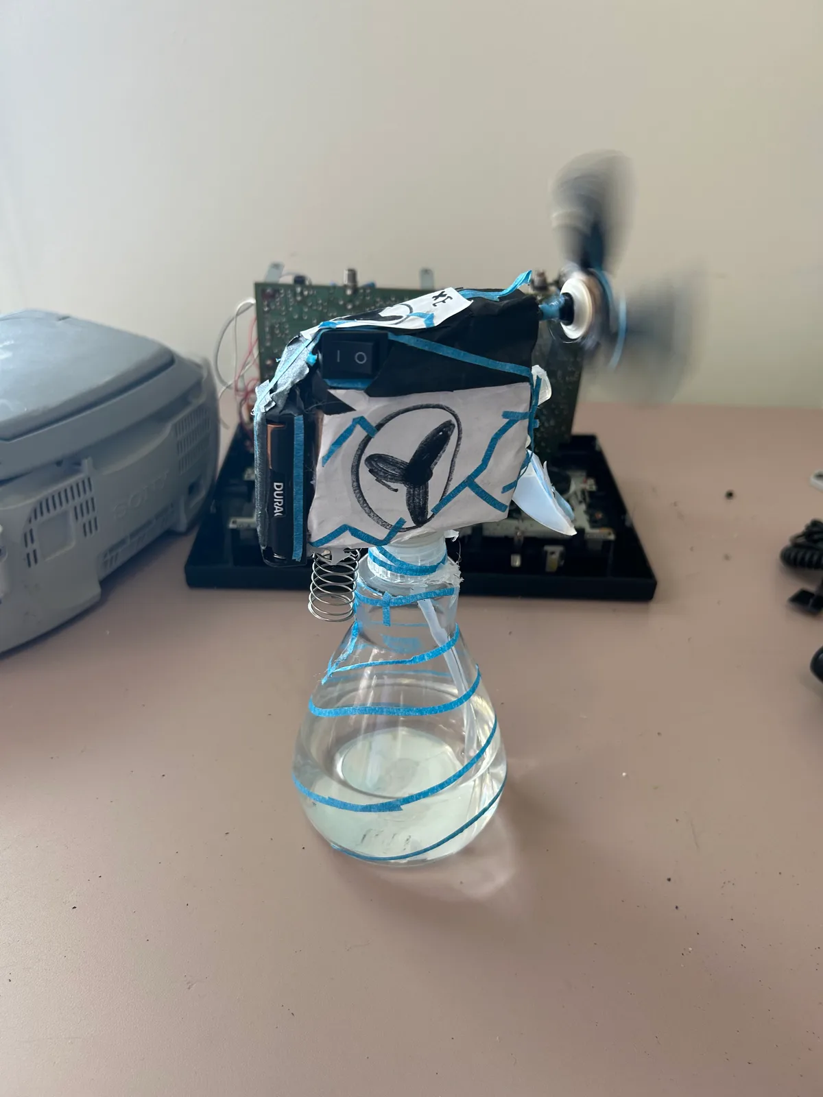 A salvaged motor spinning a propeller, mounted on a flask