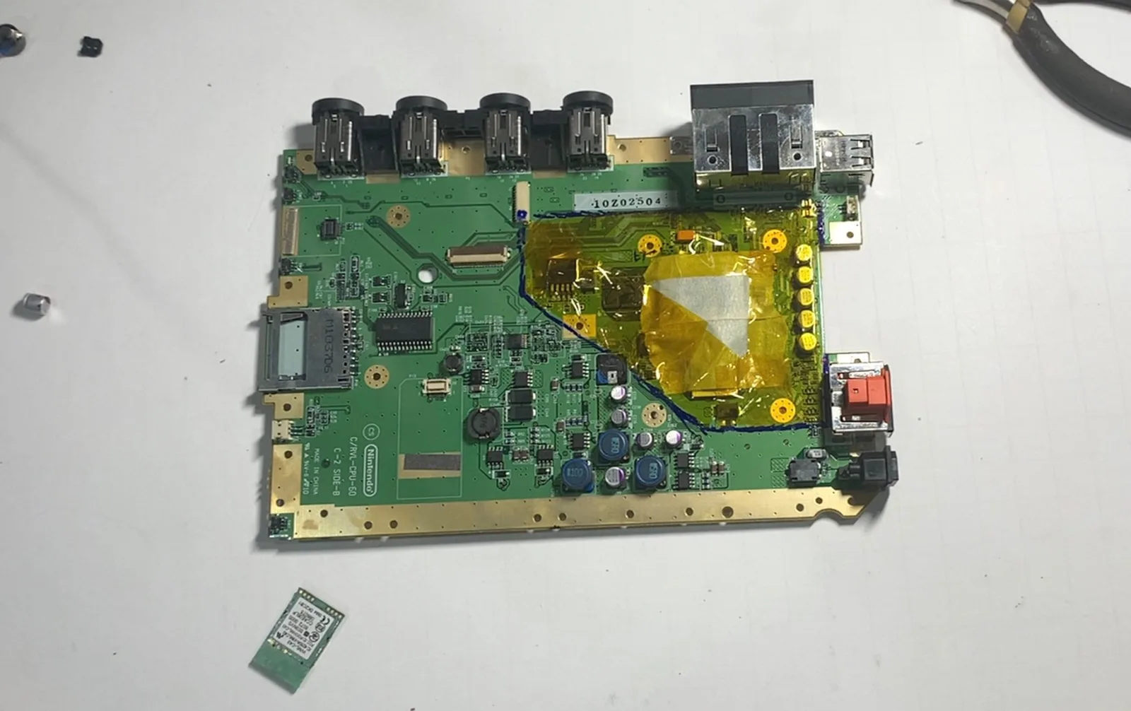 Wii motherboard with the trim line drawn and the keep area masked in Kapton