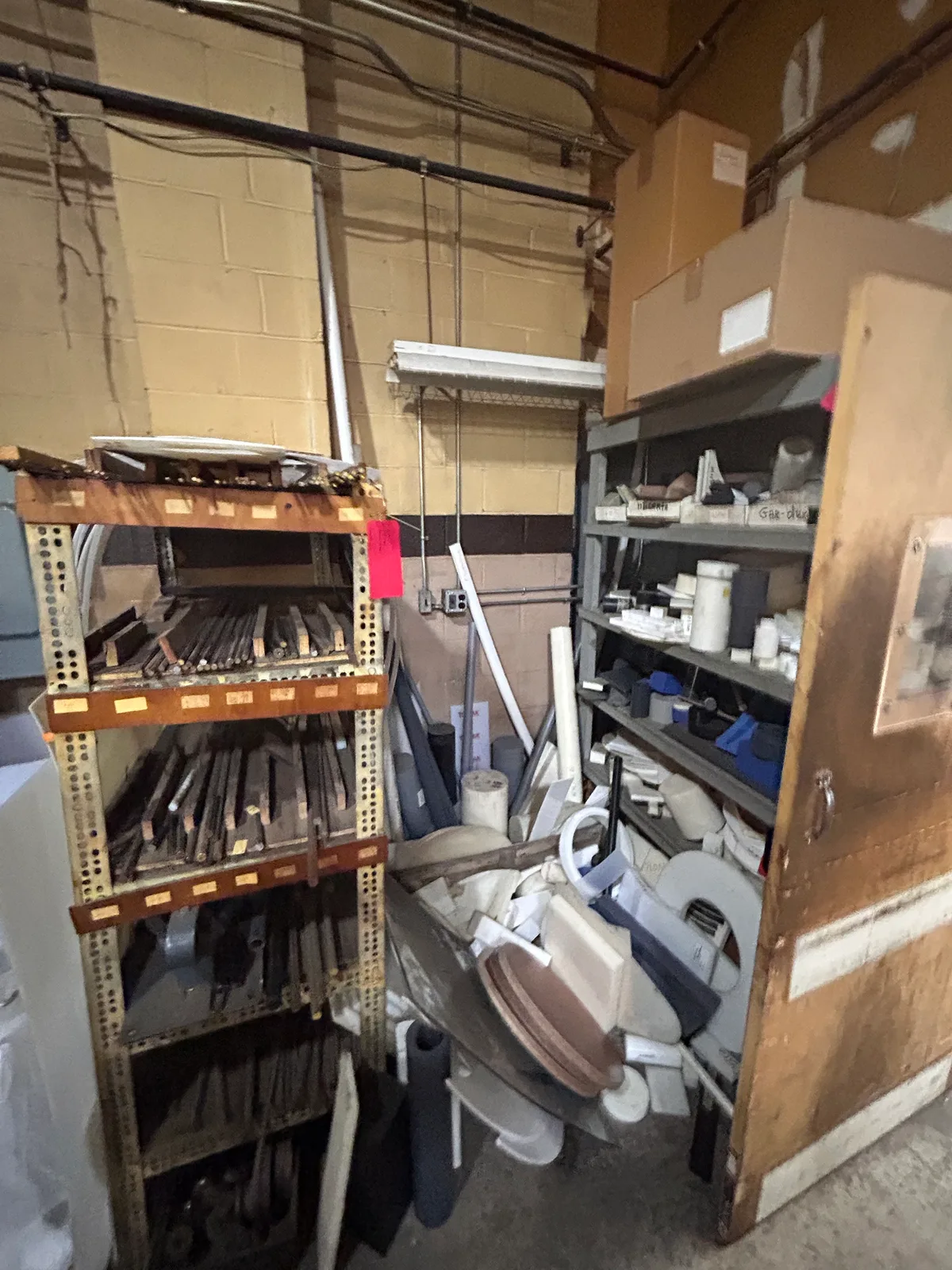 Before: plastic bar and sheet stock piled in a back-room corner beside the metal-stock rack.
